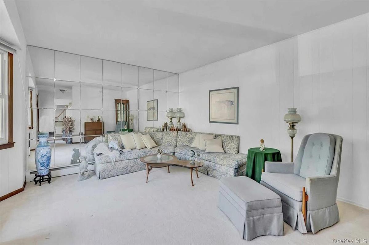 Living area featuring floor-to-ceiling grid-pattern mirrored walls and neutral carpeting