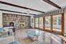 Living area featuring exposed wood ceiling beams, floor-to-ceiling stone fireplace with a raised hearth, wood-finish flooring, and multi-panel sliding