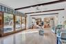 Living space featuring wood-finish flooring, exposed ceiling beams, a ceiling fan, and expansive glass sliding doors