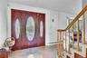 Entryway featuring a wood-finish door with decorative glass inserts, a wood-finish handrail, and carpeted stairs