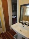 Pedestal sink with polished metal faucet, wood-finish flooring, and framed wall-mounted mirror