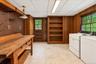 Functional utility room featuring a washer and dryer, workbench, and ample storage, with convenient direct access to the driveway.