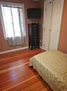 Natural wood-finish flooring, double-panel closet doors with hardware, and a window with white trim