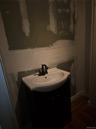 Vanity featuring a dark-finish base, white integrated sink basin, dark metallic faucet, and wood-finish flooring