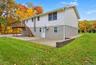 Two-story structure featuring a stucco and siding exterior, elevated wooden deck with staircase access, paved patio, and a retaining wall