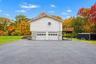 Two-story structure featuring a dual-bay garage with paneled doors, an elevated wood deck, asphalt driveway, and masonry steps