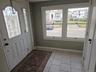 Entryway featuring a white exterior door with decorative glass inserts, ceramic tile flooring, and large windows with white trim