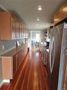 Kitchen featuring extensive wood-finish cabinetry, stone-style countertops, wood-finish flooring, recessed lighting, and stainless steel appliances