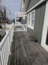 Covered deck featuring vertical siding, white railing, and exterior glass door