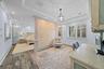 Tray ceilings with crown molding, custom partition wall with decorative finish, wood-finish flooring, recessed lighting, and plantation shutters