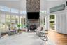 Vaulted ceiling, floor-to-ceiling stone fireplace with timber mantel, extensive window configuration with interior plantation shutters, and wood-finis