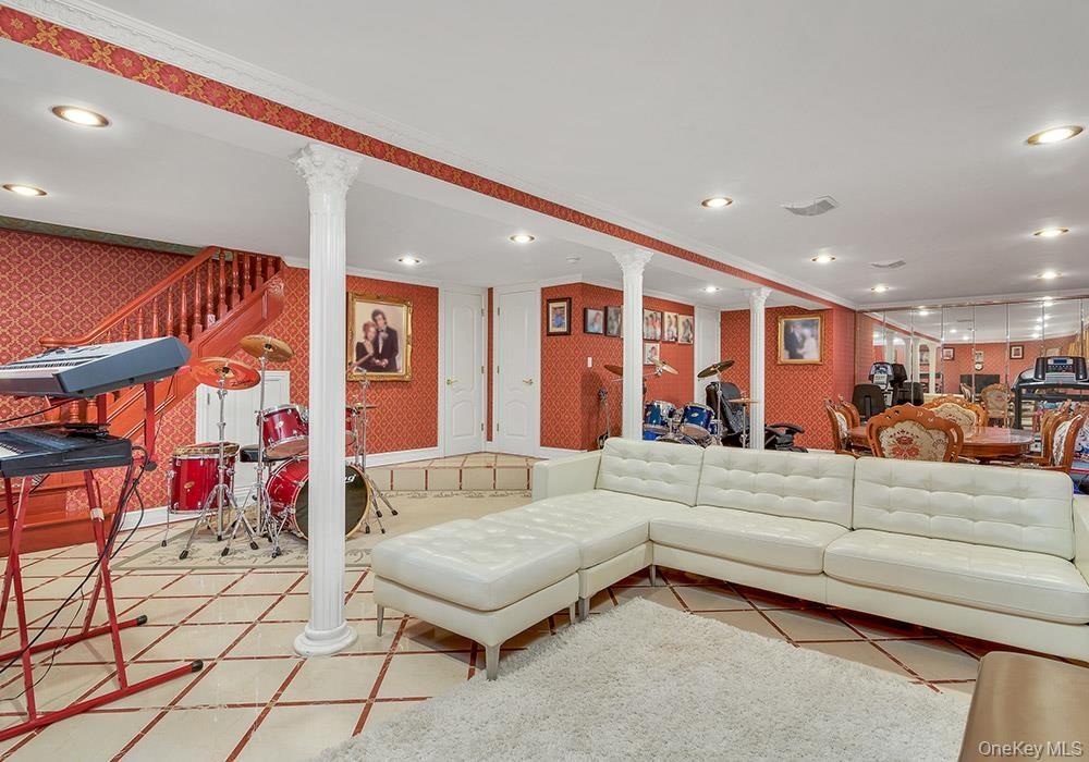 Open-plan room featuring tile flooring, classic columns, recessed lighting, and a mirrored wall