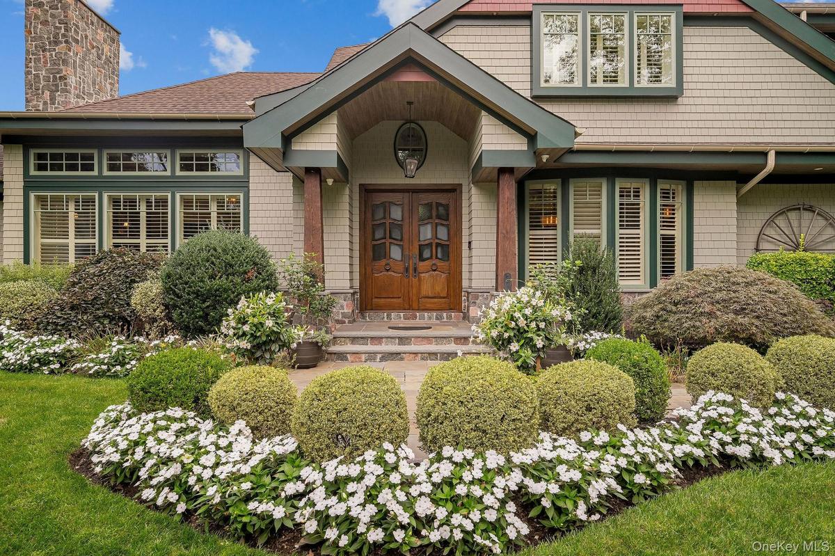 Craftsman-style exterior featuring shingle siding, a covered entryway with stone porch, custom wood double doors, and an exterior stone chimney
