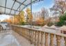 Covered terrace featuring stone-finish balustrades, large-format tile flooring, metal structural pillars, and a semi-translucent arched canopy