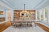 Dining area featuring wood-plank accent walls, tray ceiling, wood-finish flooring, and bay windows with plantation shutters