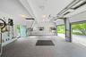 Multi-car garage featuring speckled epoxy flooring, overhead garage door system, integrated attic access ladder, and dual double-pane windows