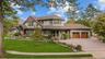 Multi-story residence featuring composite siding with stone veneer accents, an expansive paved driveway, two-car garage with carriage-style doors, and