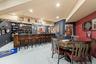 Custom wet bar featuring dark wood-finish cabinetry, recessed lighting, and large-format porcelain tile flooring