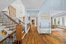 Interior featuring wood-finish flooring, a staircase with a metal railing and wood-tone newel post, an accent wall with stone masonry, horizontal wood