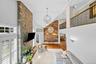 Vaulted ceilings featuring a full-height stone fireplace, reclaimed wood-finish accent wall, wood-finish flooring, and a mezzanine with wrought iron r