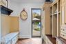 Built-in cabinetry with integrated storage, wood-finish flooring, beadboard wall paneling, and a full-light glass entry door