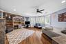 Wood-finish flooring, reclaimed wood-style plank accent wall, recessed lighting, matte black ceiling fan, and plantation shutters