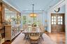 Dining area featuring wood-finish plank flooring, wood-paneled accent wall, tray ceiling with recessed lighting, bay windows with plantation shutters,