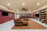 Large recreation space featuring polished tile flooring, recessed lighting, ceiling fan, and extensive built-in wood shelving