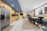 Kitchen featuring stainless steel refrigerator, light wood cabinetry, stone-texture backsplash, recessed lighting, and large-format tile flooring