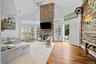 Vaulted ceiling with a full-height stone fireplace, wood-plank accent wall, wood-finish flooring, and plantation shutters