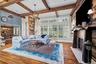 Living area featuring exposed wood ceiling beams, wood-finish flooring, a floor-to-ceiling wood plank accent wall, a fireplace with a live-edge wood m