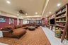 Spacious room featuring floor-to-ceiling built-in wooden shelving, recessed lighting, tile flooring, and French doors