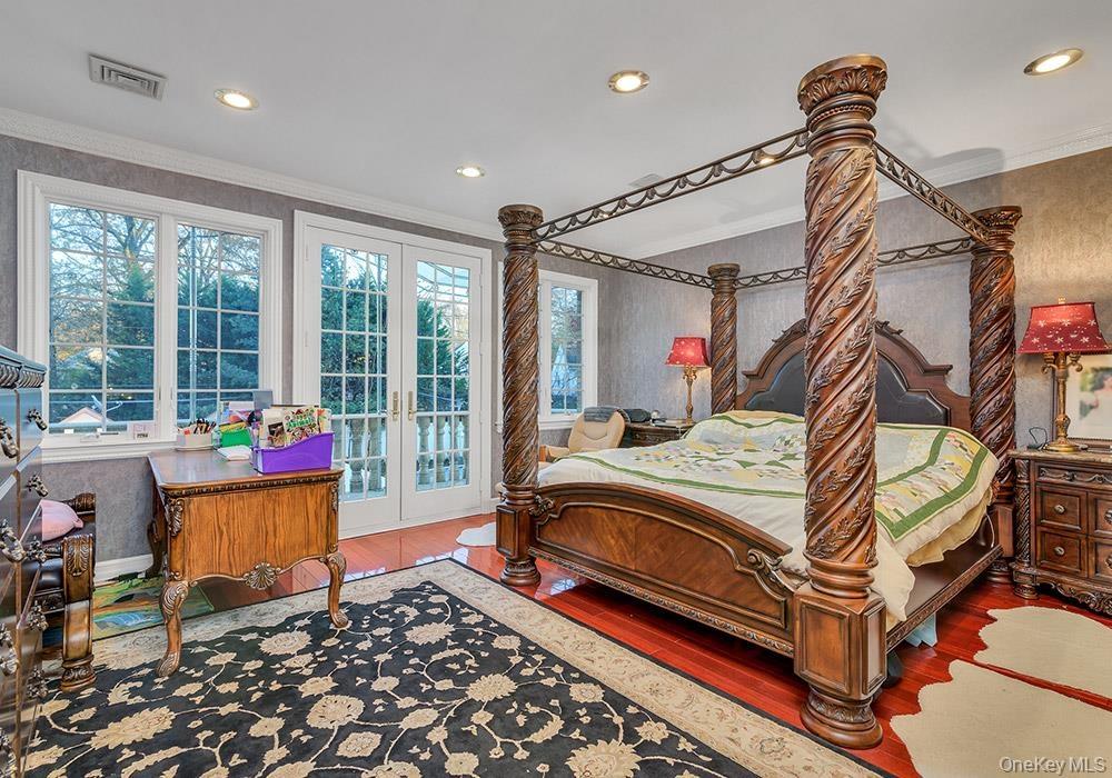 Room featuring cherry-finished hardwood flooring, crown molding, recessed lighting, and double glass-paned doors with exterior access