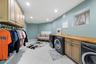 Dedicated laundry room featuring tile flooring, neutral wall-mounted cabinetry, an expansive wood-finish folding counter, and recessed lighting