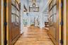 Double front doors featuring wood construction and glass inserts, wood-finish flooring, two-story ceiling height, intricate metal stair railing, and s
