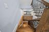 Staircase featuring wood-finish treads, custom metal railings, and a horizontal wood-plank accent wall