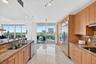 Full-height cabinetry with stainless steel appliances, granite countertops, and light-toned tile flooring