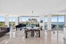 Expansive living area with polished tile flooring, floor-to-ceiling windows, and abundant natural light