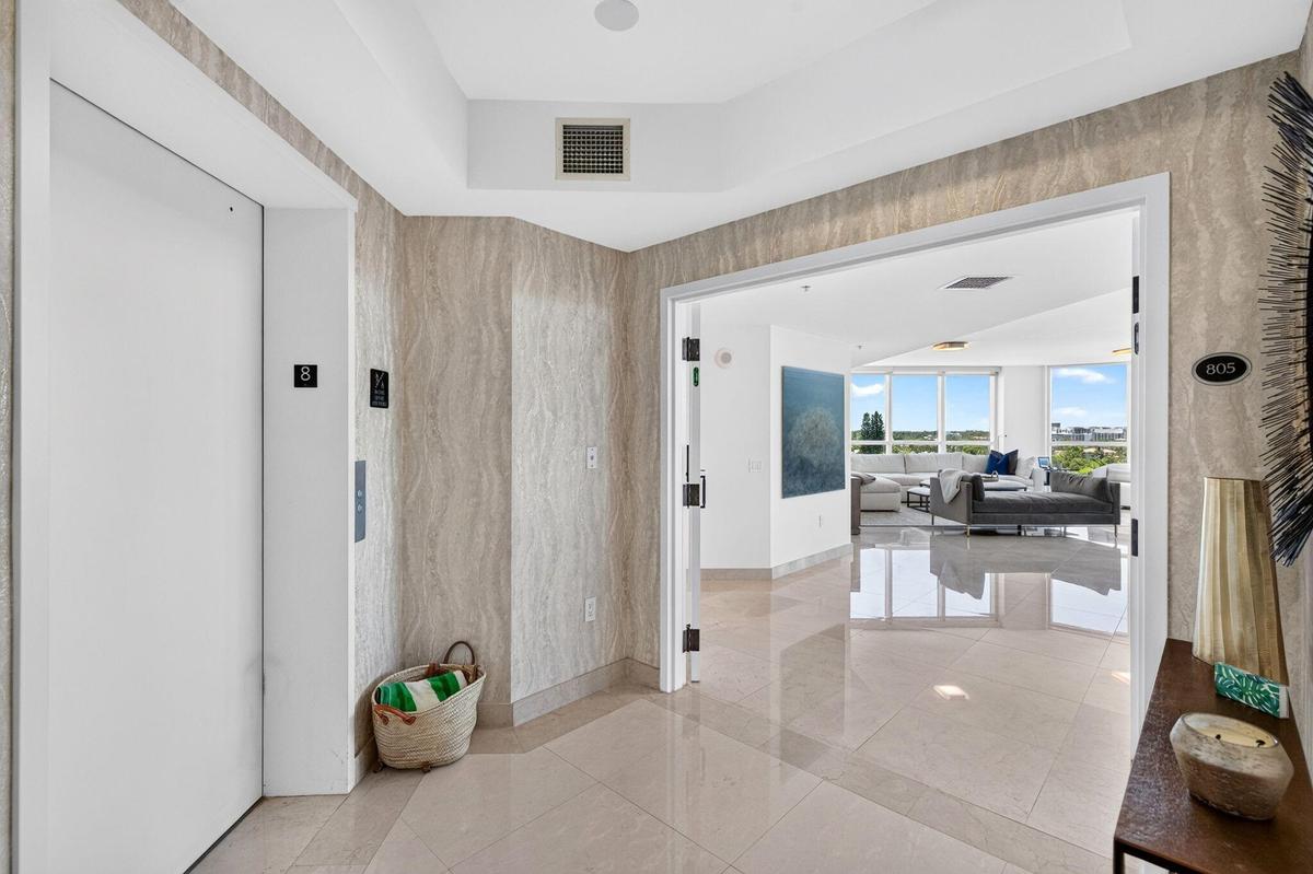 Elegant foyer featuring light wood-finish wall paneling, polished tile flooring, and dual white painted doors with modern hardware