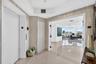 Elegant foyer featuring light wood-finish wall paneling, polished tile flooring, and dual white painted doors with modern hardware