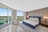 Expansive window wall, textured accent wall, polished marble flooring, recessed lighting, and balcony access