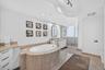 White soaking tub with integrated jets, dual vanity with undermount sinks, glass-enclosed shower, and tile flooring