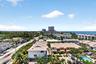Aerial perspective showcasing the residential community with mature tropical landscaping, resort-style swimming pool, multi-unit architecture with tan