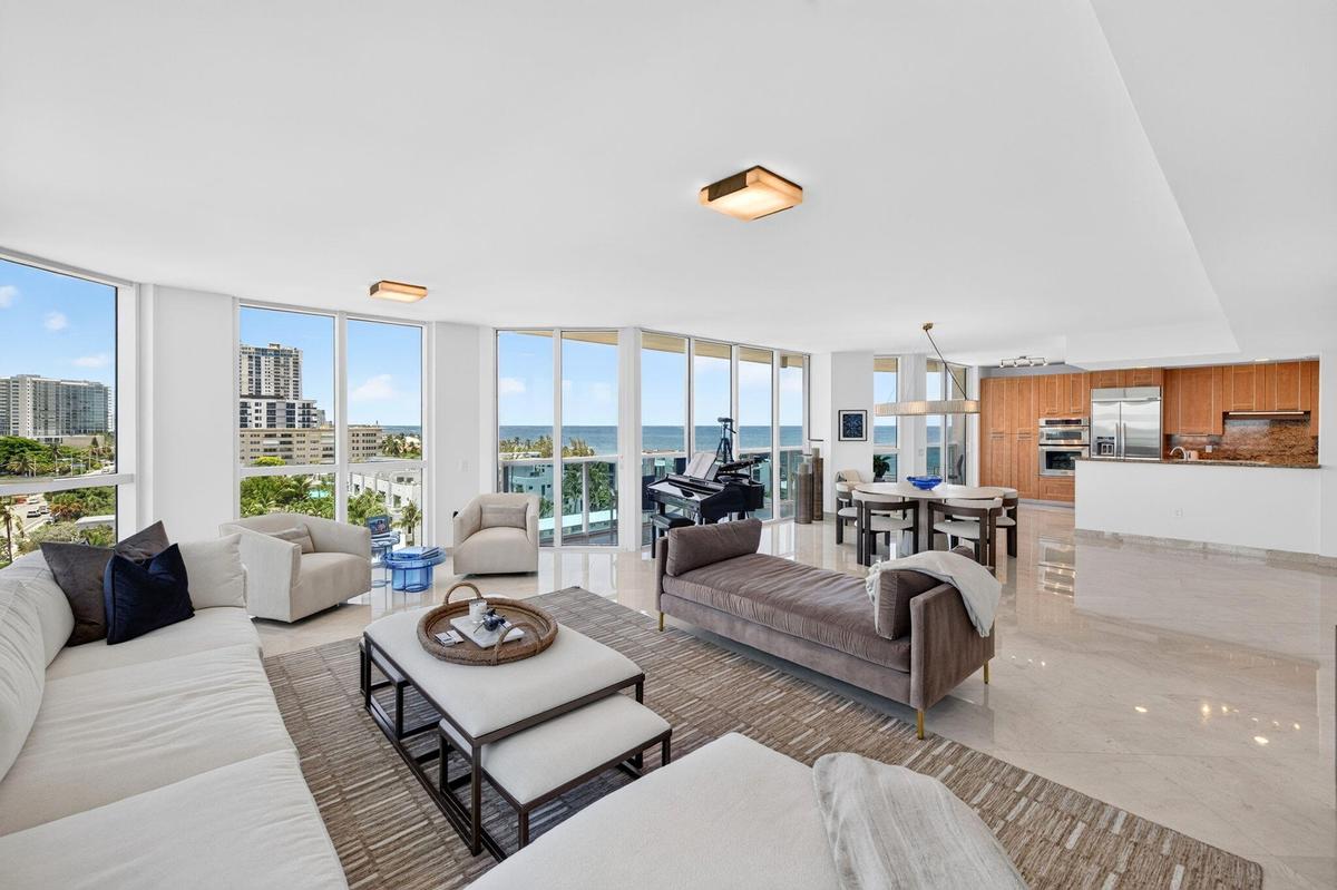 Expansive floor-to-ceiling windows, light-toned tile flooring, open concept layout, wood-finish kitchen cabinetry, and integrated stainless steel appl
