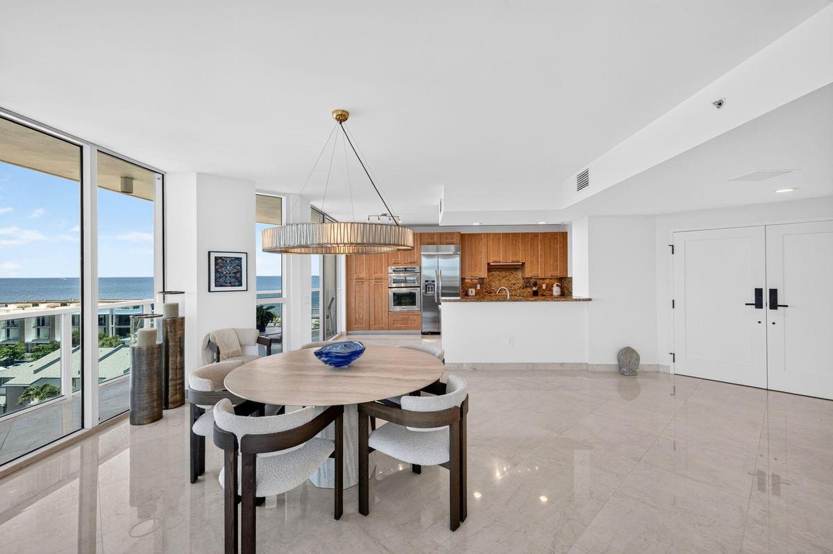 Floor-to-ceiling windows, light-toned polished flooring, modern kitchen with wood cabinetry, stainless steel appliances, and double panel interior doo