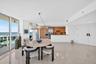 Floor-to-ceiling windows, light-toned polished flooring, modern kitchen with wood cabinetry, stainless steel appliances, and double panel interior doo