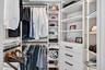 Custom closet system featuring integrated lighting, multiple shelving units, and built-in drawers with black hardware