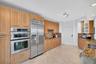 Light wood-finish cabinetry with stainless steel appliances, granite countertops, and marble flooring