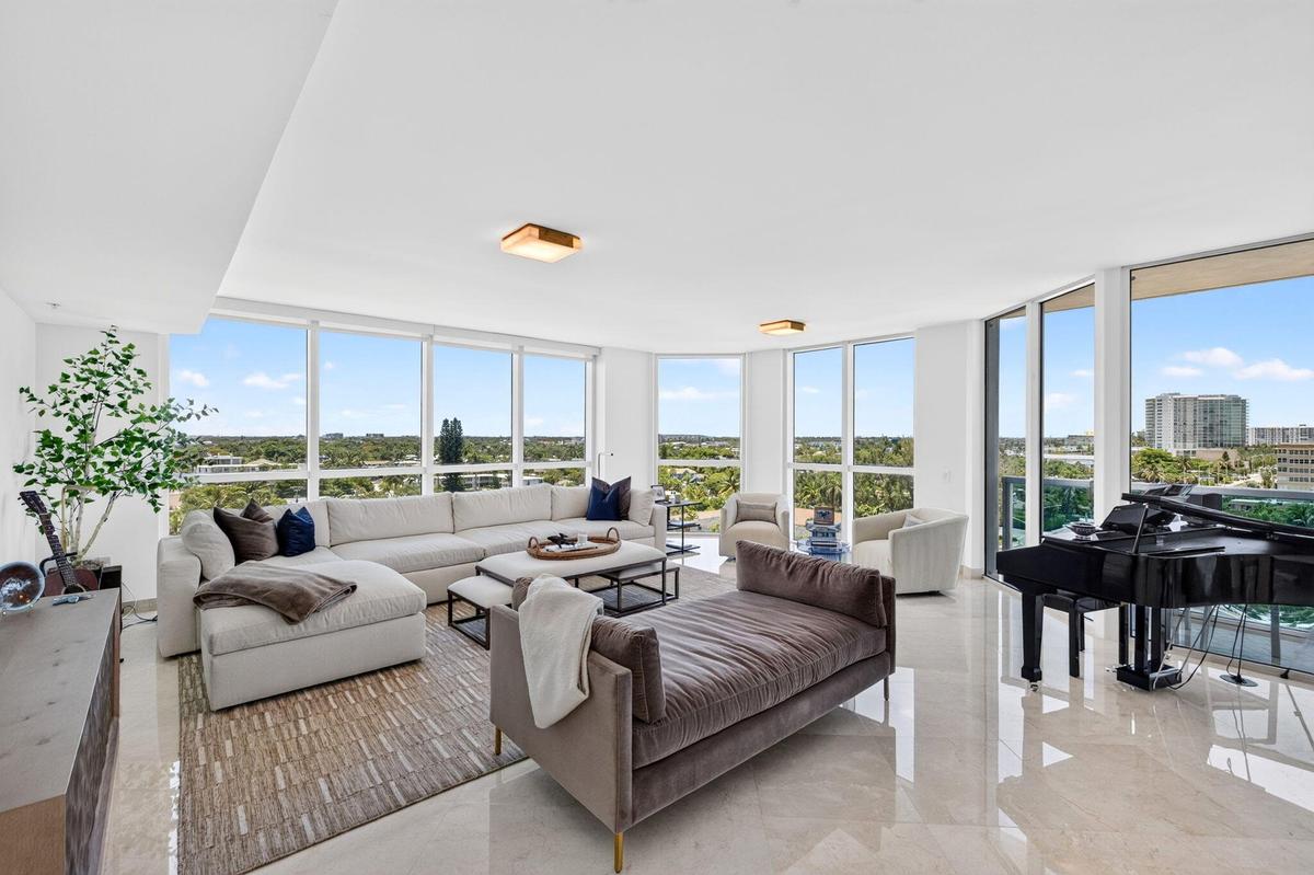 Expansive living area with floor-to-ceiling windows, light-toned tile flooring, and recessed ceiling lighting