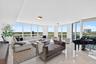 Expansive living area with floor-to-ceiling windows, light-toned tile flooring, and recessed ceiling lighting